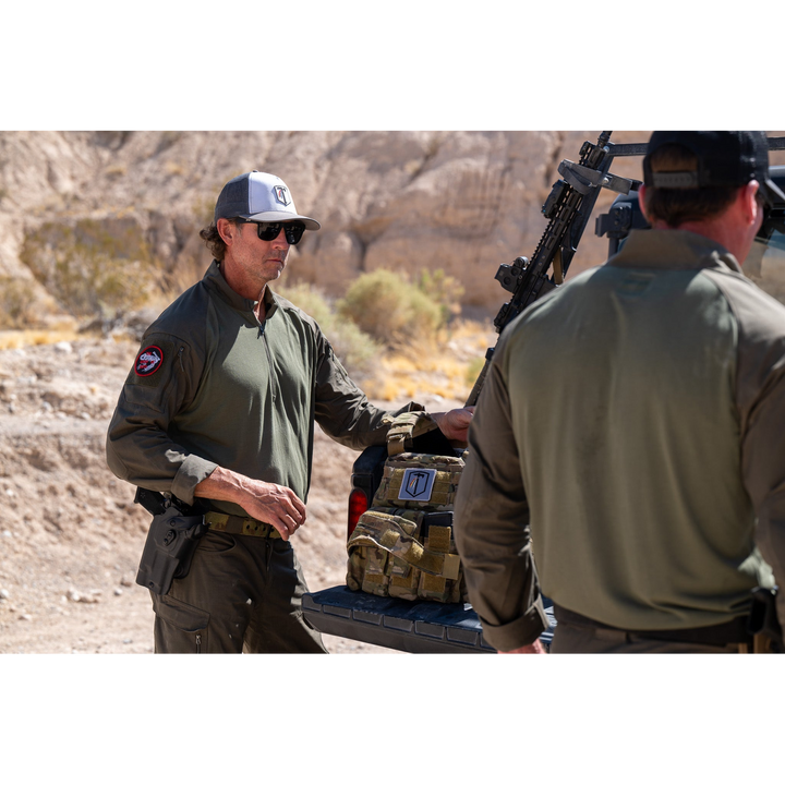 Photo of a man wearing the Tomahawk Performance HW / Combat Uniform putting on an S&S plate carrier.